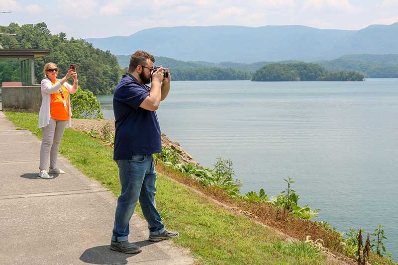 Man looking through binoculars at lake