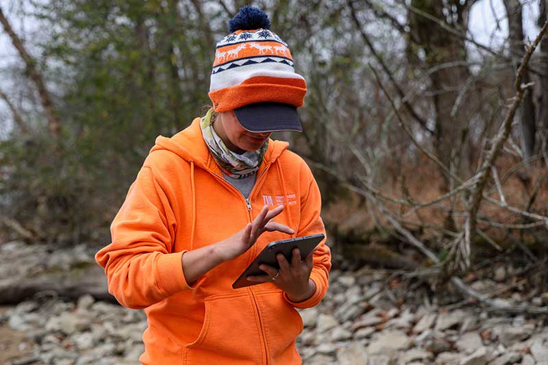 Person in winter hat and hoodie on a tablet in the cold