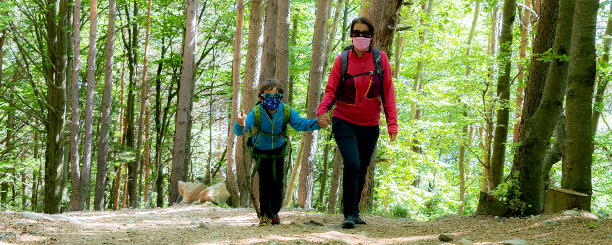 Mom and son wearing face masks due to COVID-19 walking on a trail