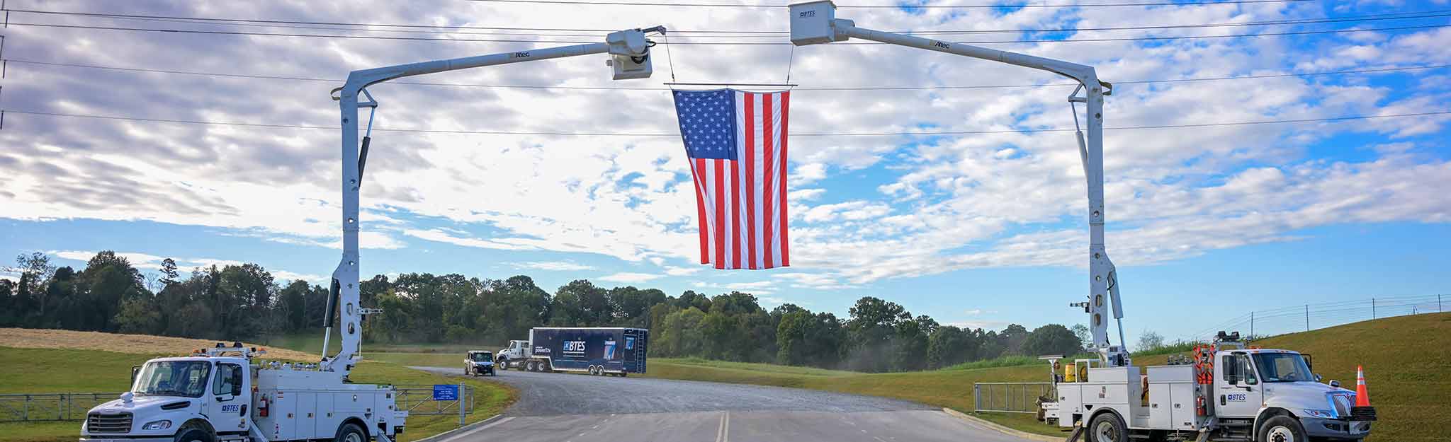 American flag flying from two bucket trucks