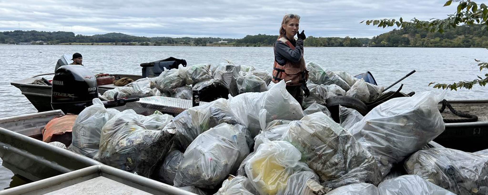Two trash boats overflow with bags of litter