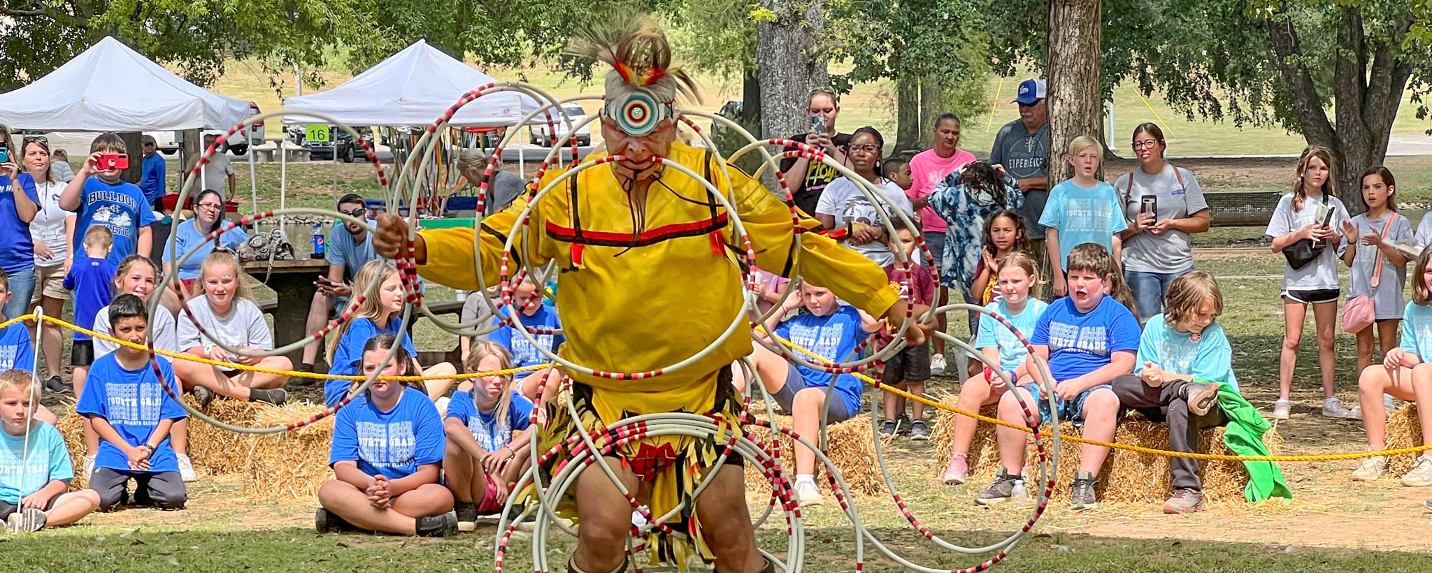 A Native American hoop dancer leads a demonstration for a large group of school children at the Oka Kapassa Native American Festival in Tuscumbia, Alabama