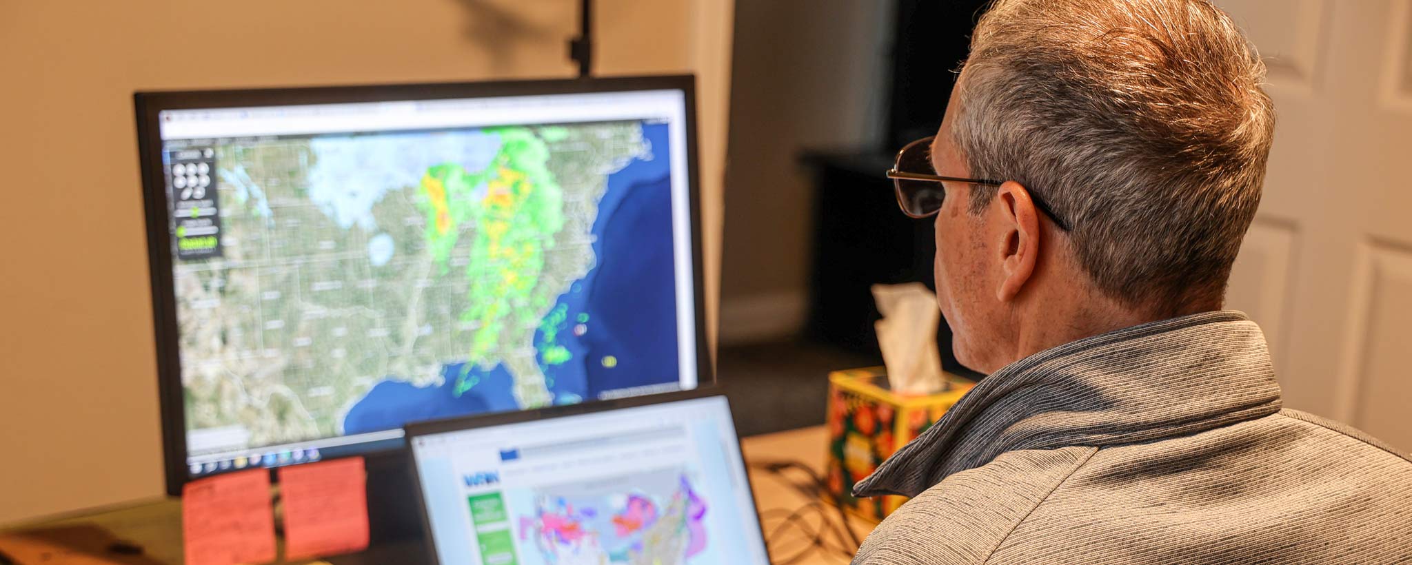 Meteorologist studying weather pattern on computer screens