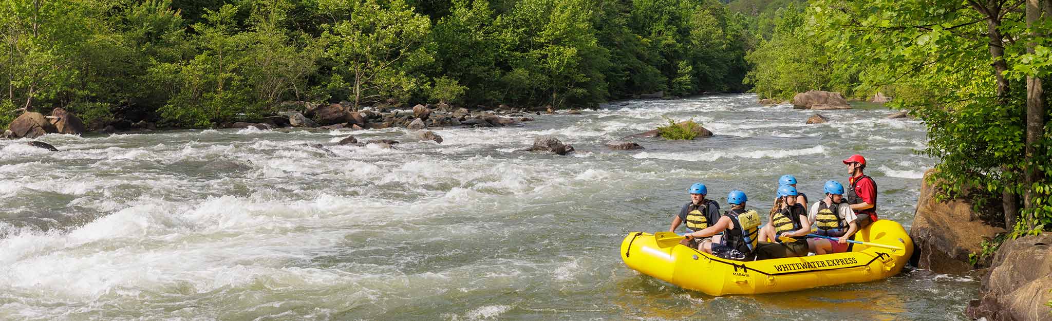 A 2024 rafting group prepares to launch by pushing off the bank into the current.
