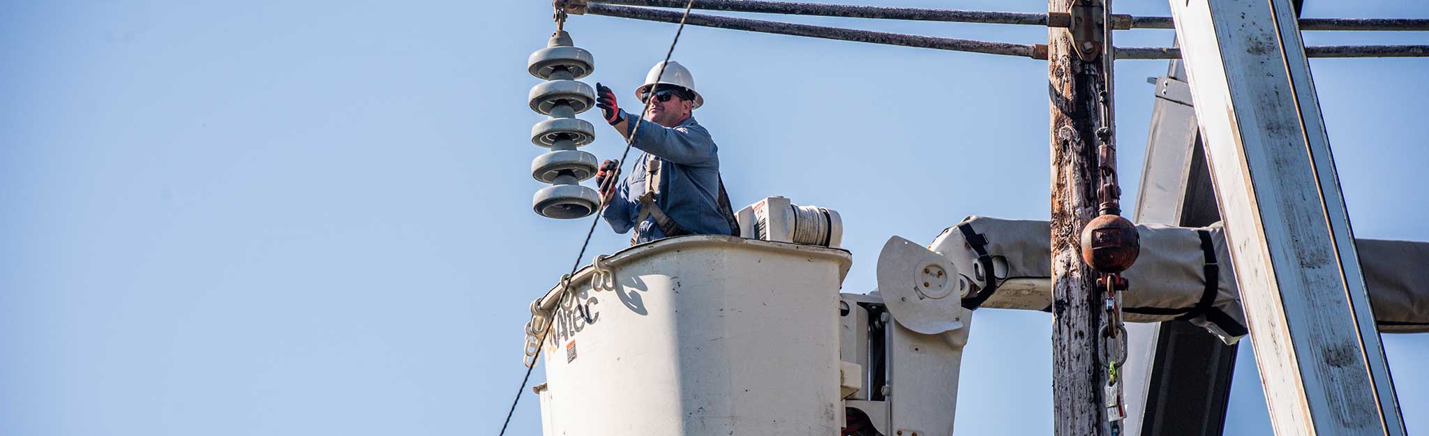 TVA lineworker in a bucket lift working on the insulators of a power line