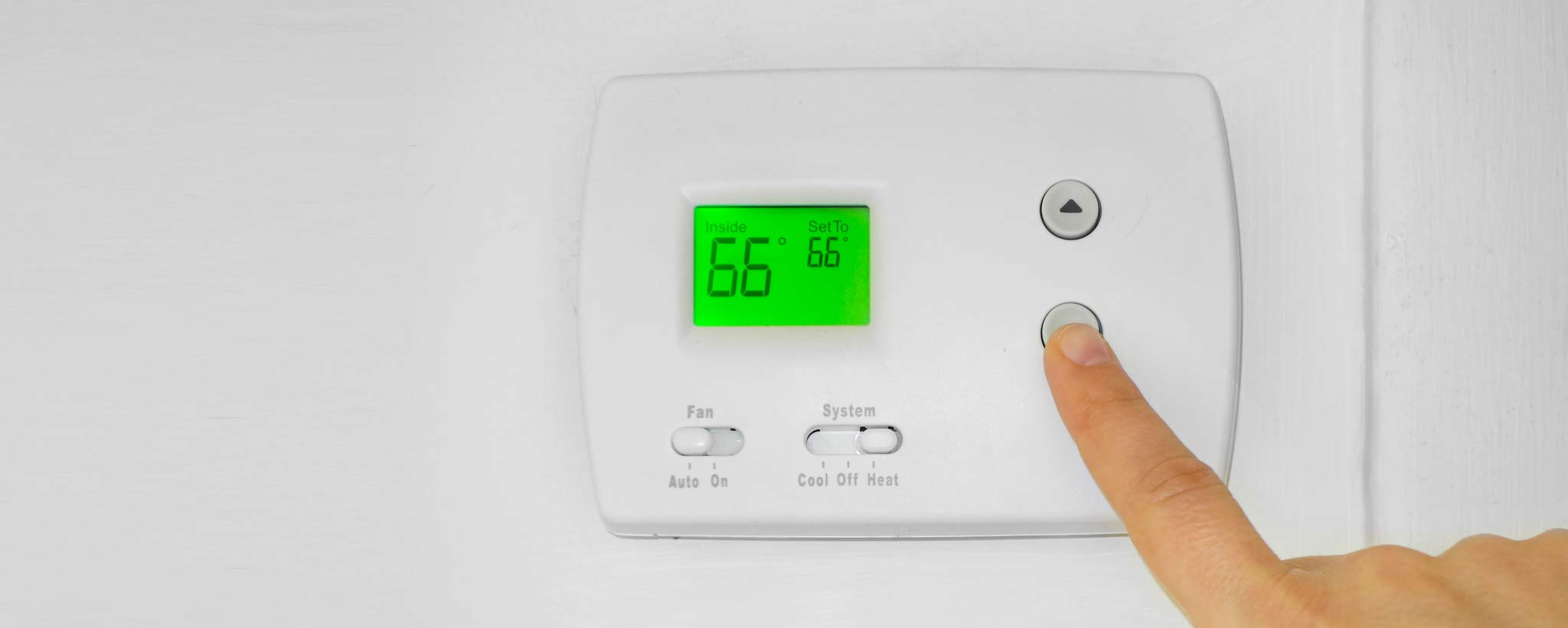 Thermostat-hero Person adjusting a wall thermostat temperature