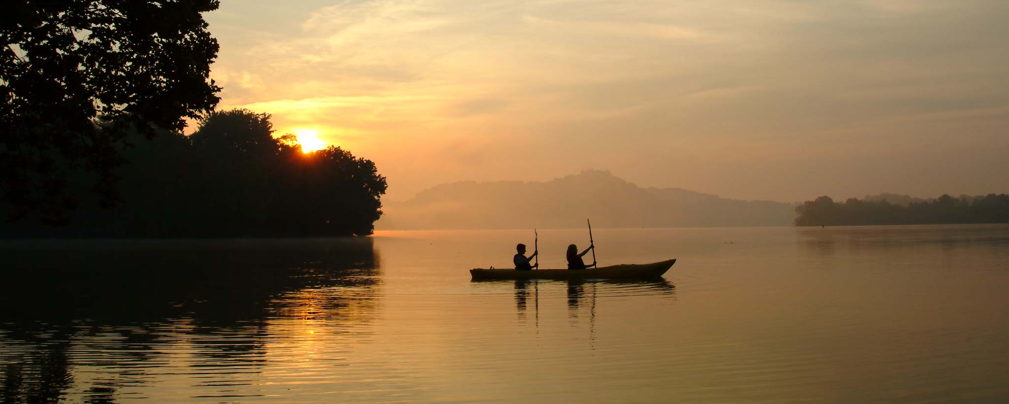 Two people canoeing on a lake at sunset