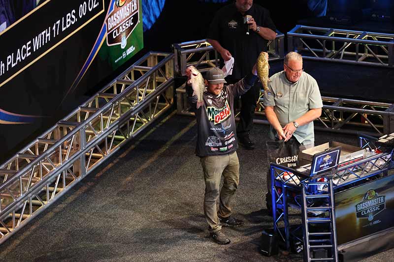 Participant holds up two fish to be weighed