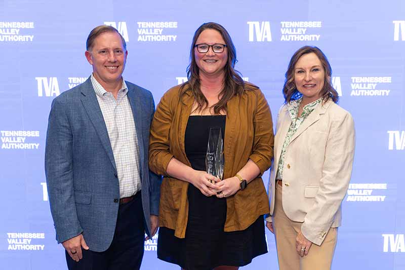 Woman with award with TVA presenters at her sides.