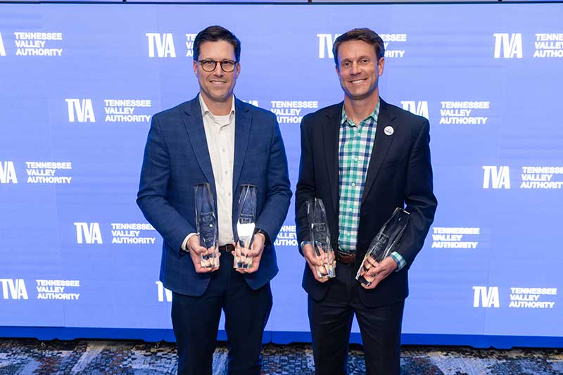 Two men display their awards.