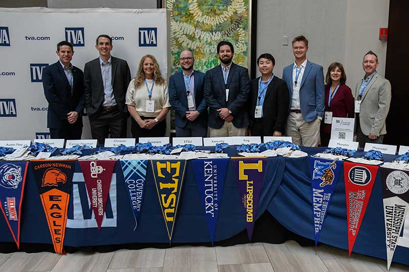 TVA representatives behind a table featuring pennants from participating schools