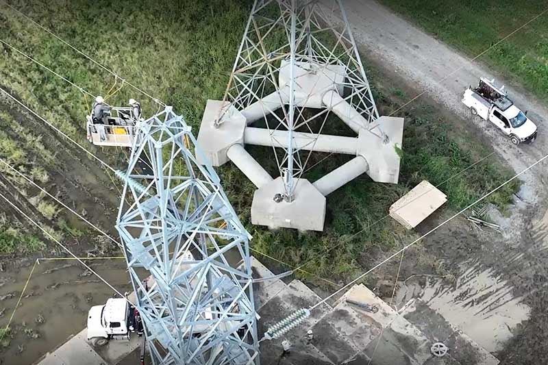 Aerial view of lineworkers working high up a transmission tower
