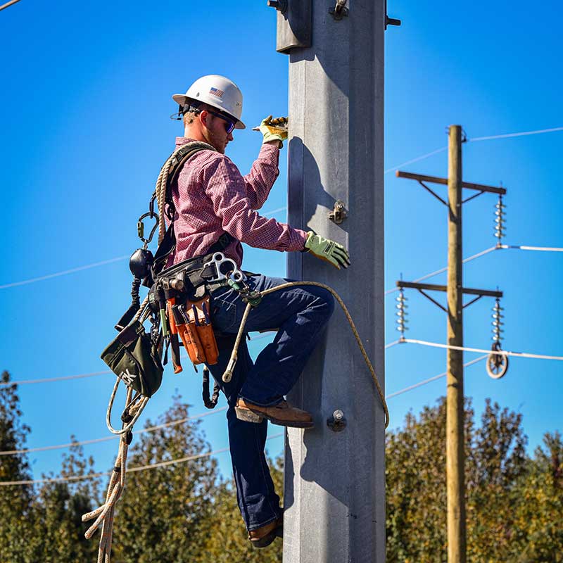 Lineworker climbing a power pole during training