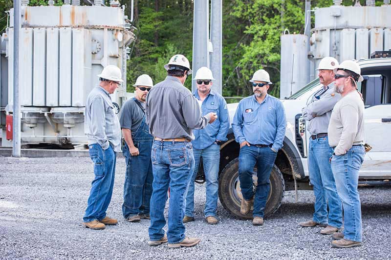 Maintenance lineworker crew members Jimmy Hinch, Matt Sweatt, James Ray Smith, Josh Hinch, Robert Hayes, Michael Simmons and Dewayne Strader conduct a pre-job brief at a site in Dayton, Tennessee.