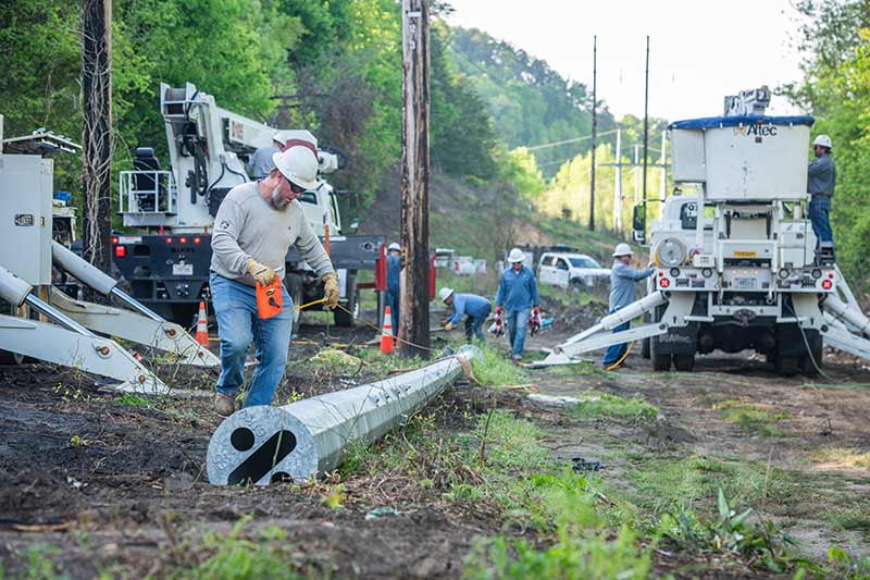 Strader takes measurements before the crew installs a steel pole.