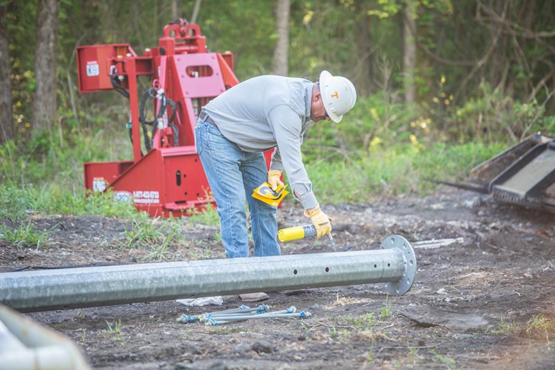 Simmons uses a torch to ready a steel pole for numbering.