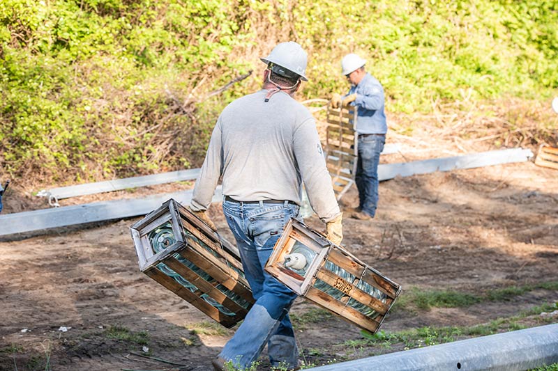 Crews unpack new insulators for steel poles.