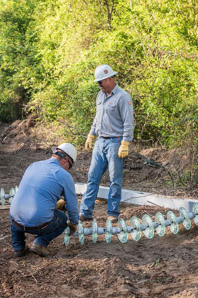 Hayes and Simmons prepare insulators for installation.