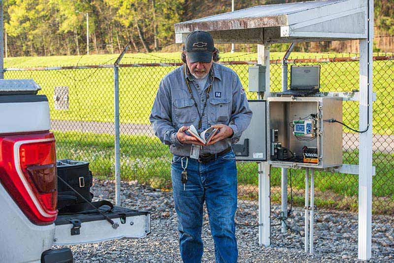 TVA senior instrument mechanic Ralph Nunley references a written record of rain gauge measurements