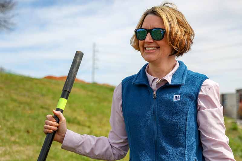 Woman in TVA vest holding a shovel