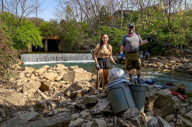 Volunteers next to stream with trashcans full of trash