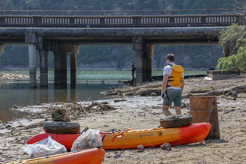 Kayaks on river bank loaded with trash