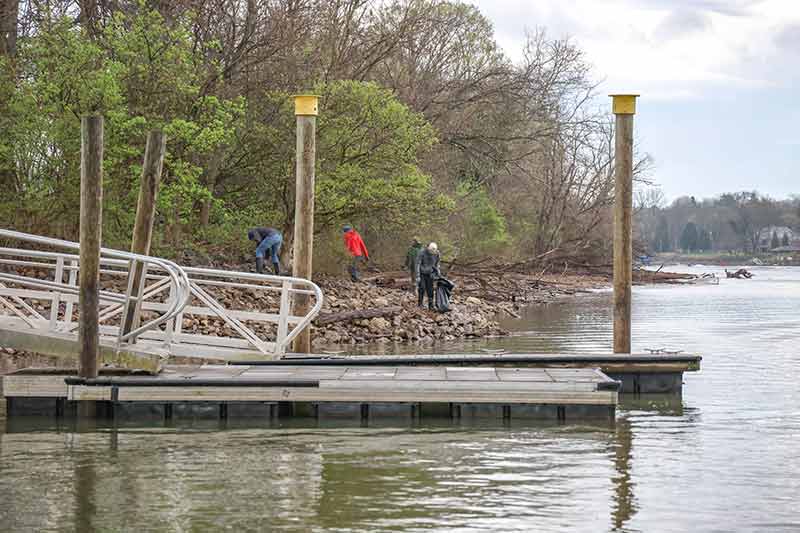 Volunteers walking along riverbank with dock in foreground