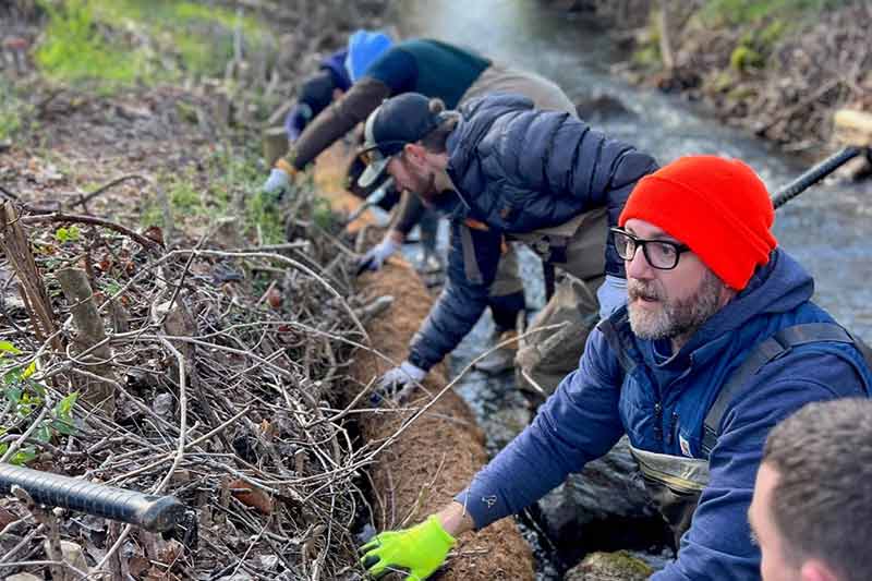 Volunteers plant trees along river edge