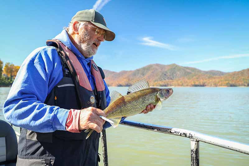 Man holding fish with lake in background