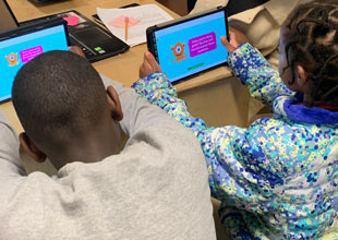 Two kids learning using a digital tablet