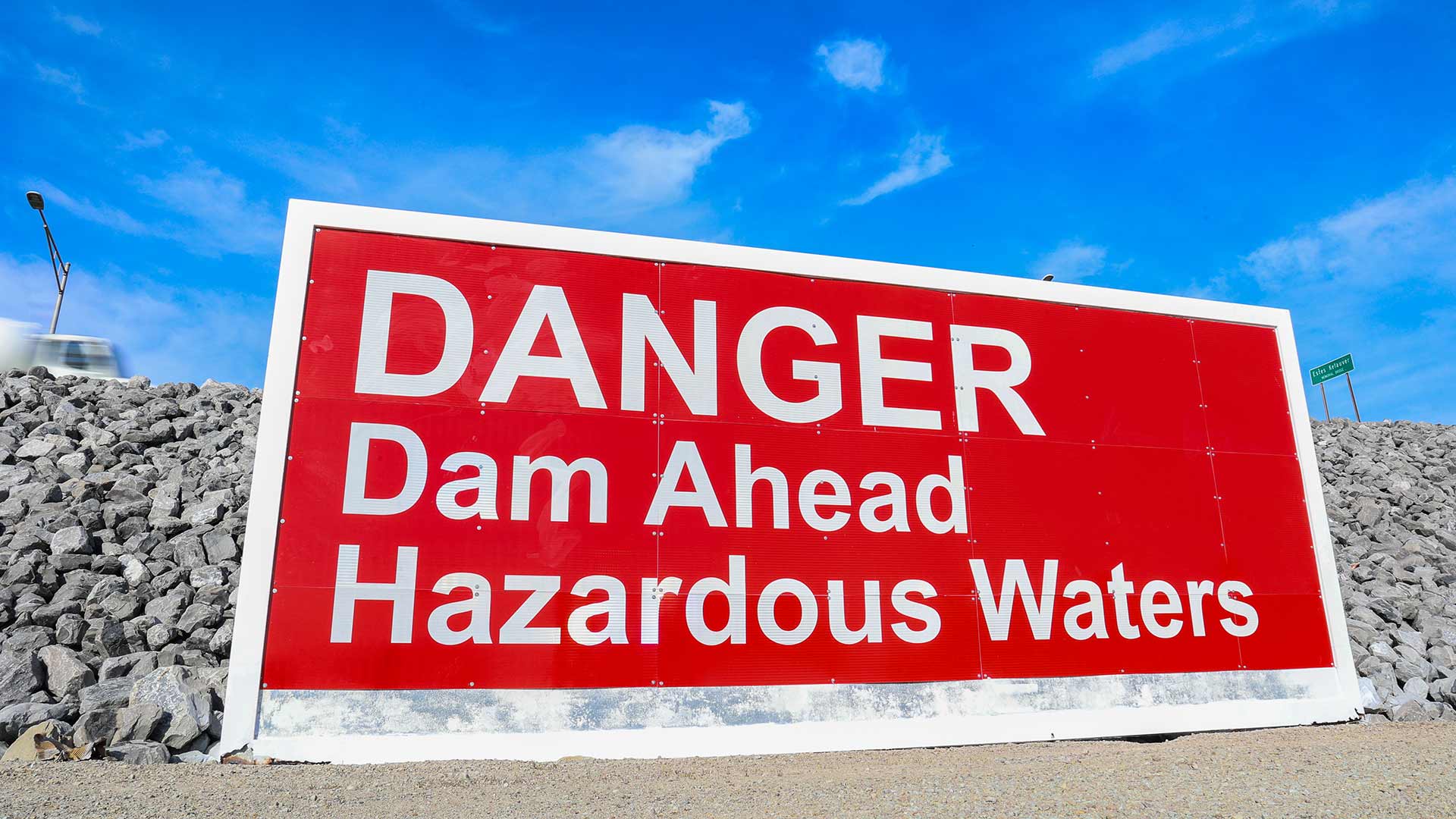 Signs warning of a dam ahead and hazardous waters.