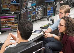 A group of students standing and observing the activity at a power trading floor