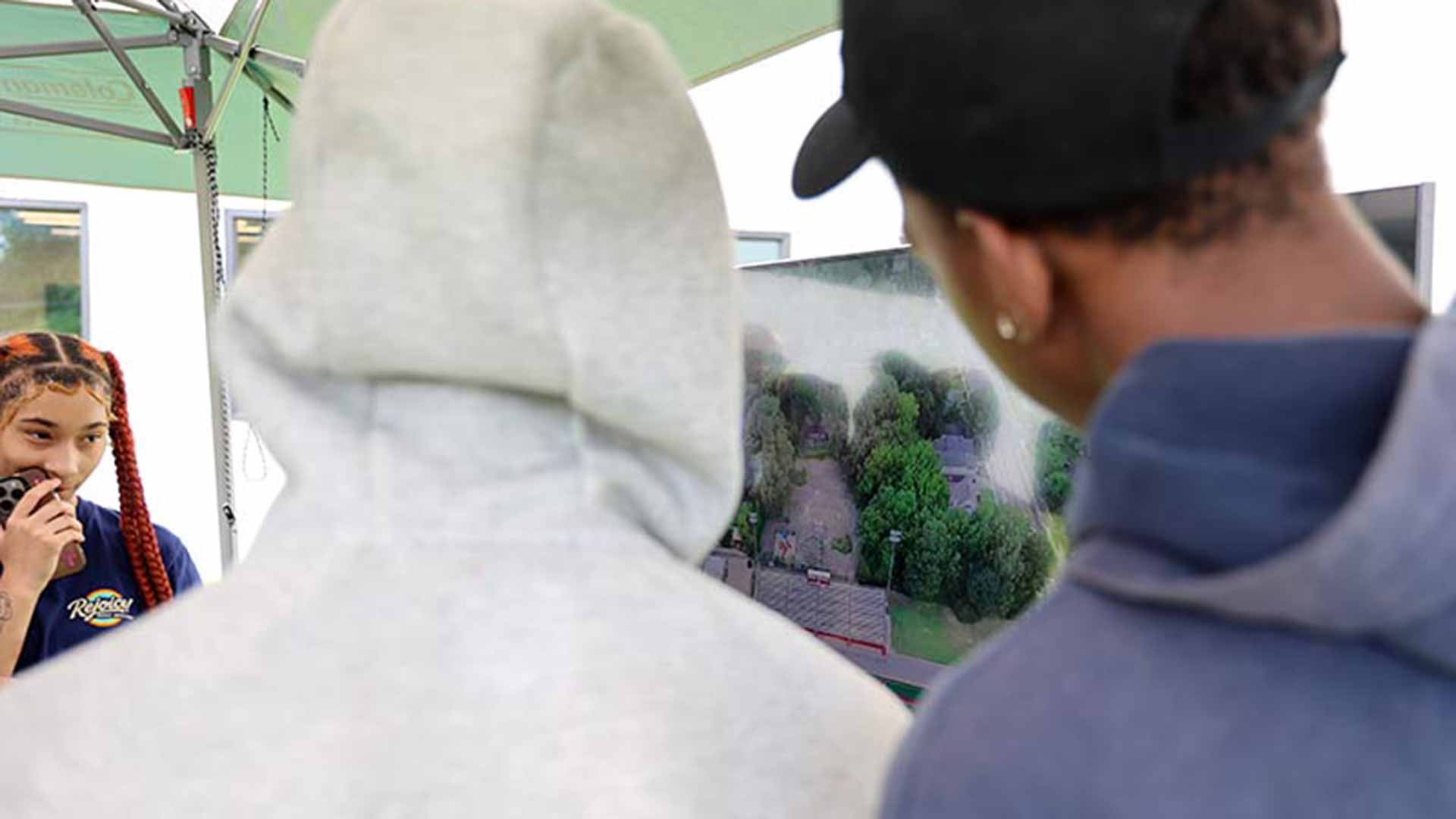 Students view a video screen displaying a live feed of the drone's camera as it flies over a football field.