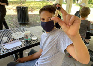 Water monitoring kids thumbnail Kid holding water testing vial