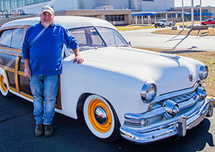 Wayne Davis standing in front of a white 1951 Ford Country Squire Woody Wagon.