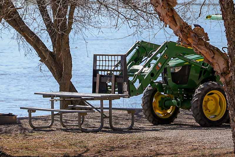 Placing picnic tables at campsites with a tractor.