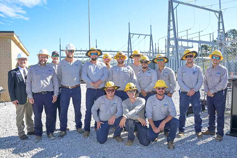 Group wearing hard hats in front of substation