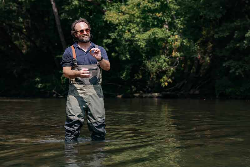 Man in waders holds up mussel