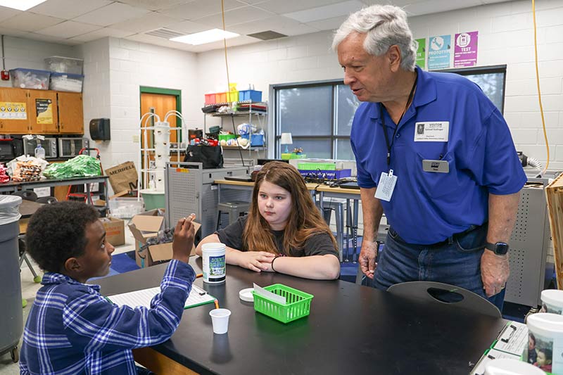 TVA retiree and Bicentennial Volunteers, Inc member Sam Esslinger helps students test water.