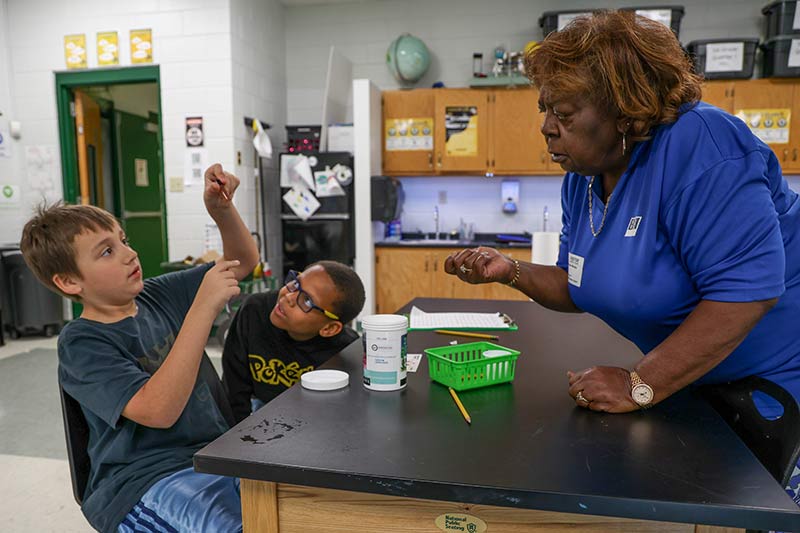 TVA retiree and Bicentennial Volunteers, Inc. member Wanda Mosley helps students test water.