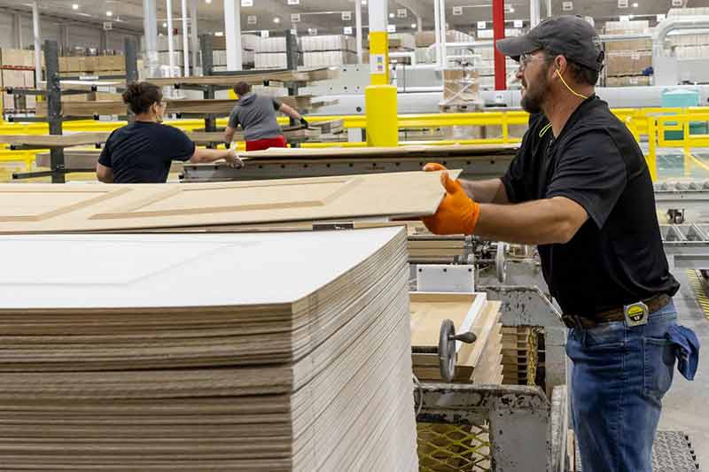 Worker moving sheets of building materials