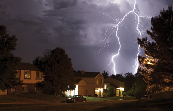 Lightning bolt and thunderhead storms over neighborhood homes