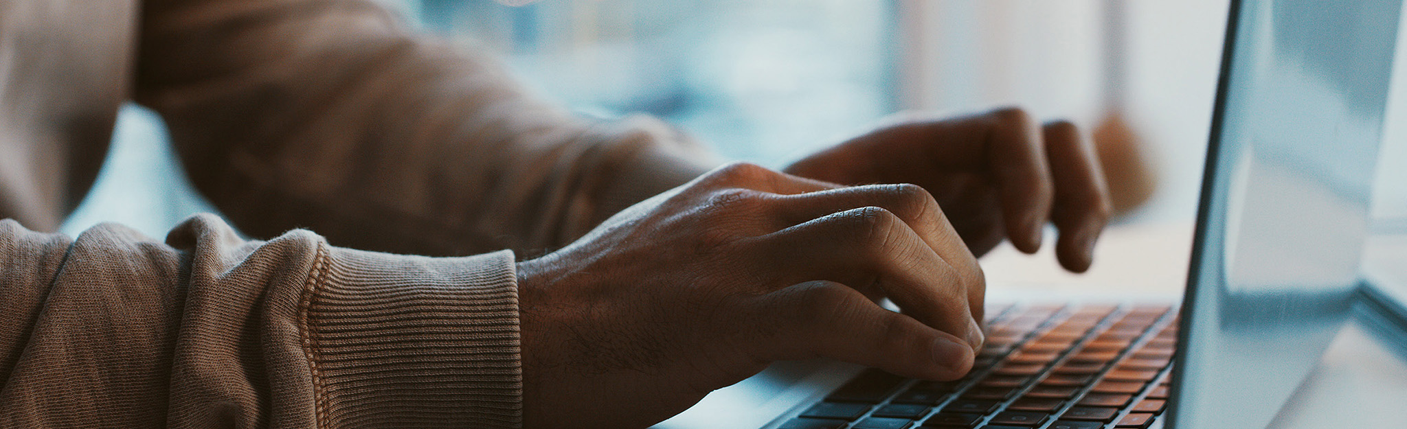 Close-up of a person typing on a laptop keyboard