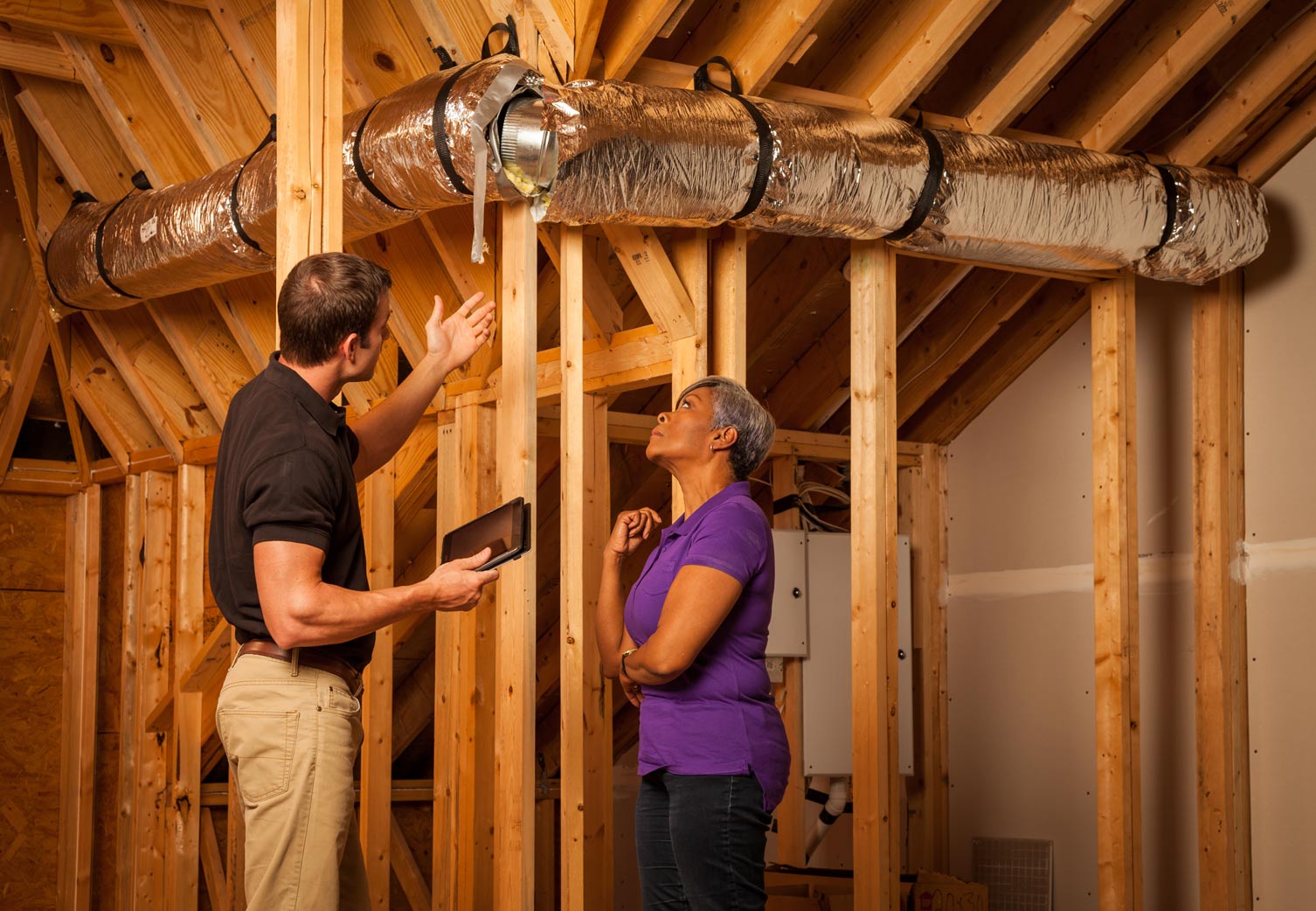 An inspector explaining attic ductwork to a home owner