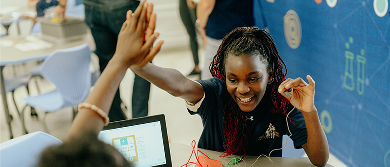 Two girls high-fiving in a computer class