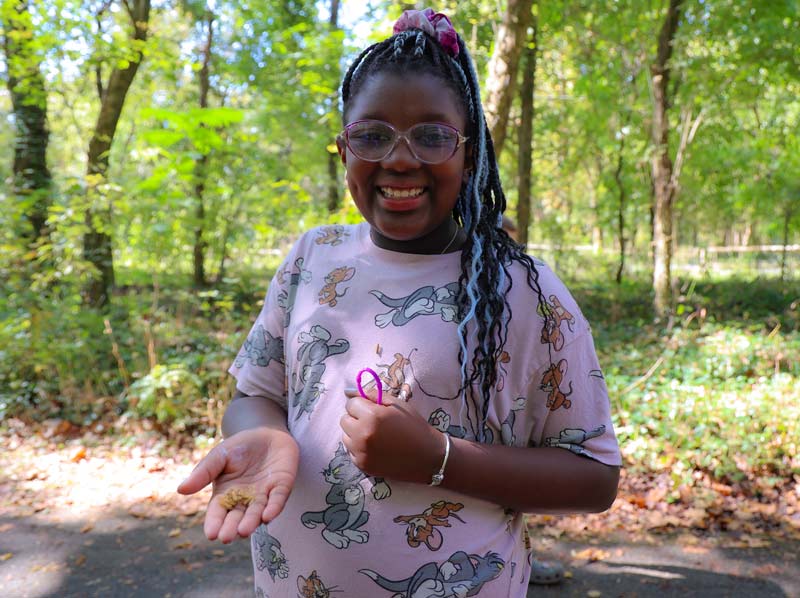A girl holds seed pods in her hand while hiking through Ijams Nature Center