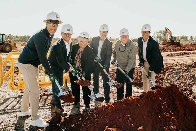 Group wearing hard hats and holding shovels
