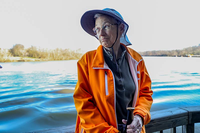 Nature program participant smiles as she stands along riverfront trail