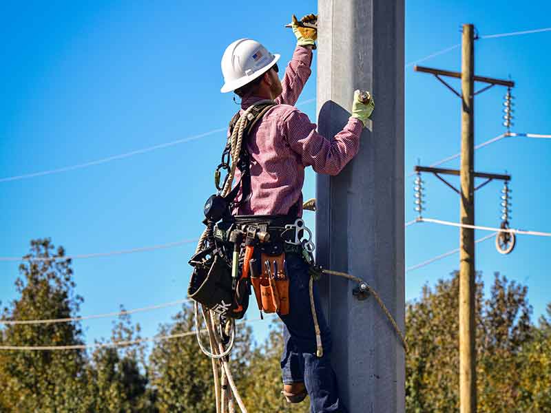 LIneworker apprentice climbing transmission pole at TVA training facility in Alabama