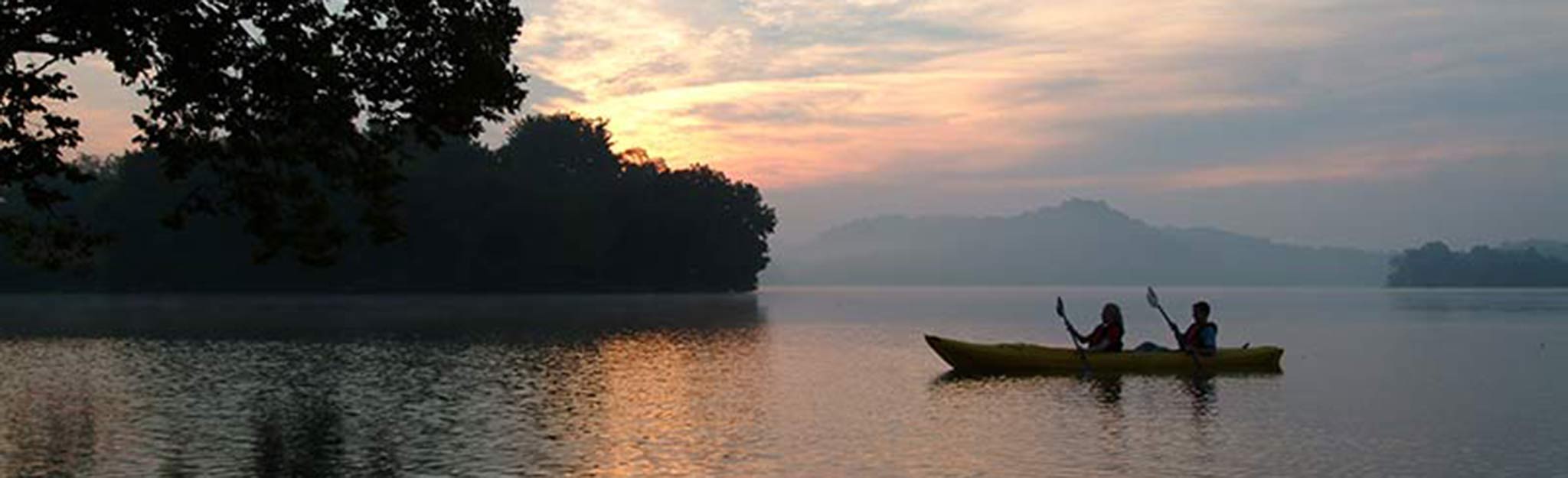 Canoeing at sunset Two people canoeing on lake at sunset